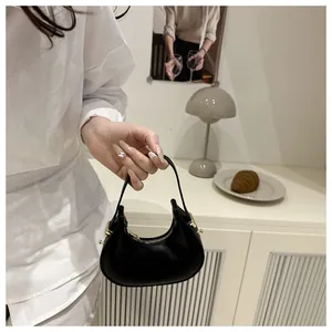 Detail of a chic black leather crescent mini handbag with gold zipper and stud accents