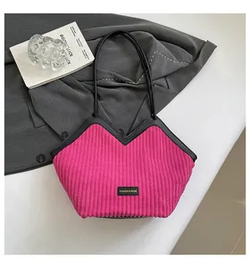 Detail of fuchsia corduroy shoulder bag with black leather trim and fashion label
