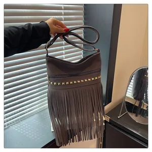 Détail d'un sac bandoulière gris rétro avec des franges stylées et des rivets dorés