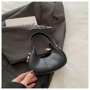 Detail shot of a black leather crescent bag with elegant gold zipper on grey suit background