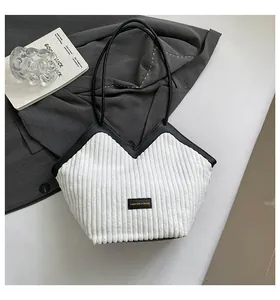 Detailed texture of white corduroy shoulder bag with black leather strap and square logo