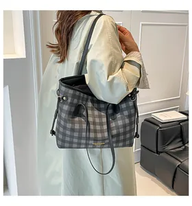 Close-up of a black and grey checkerboard tote bag worn over the shoulder by a model