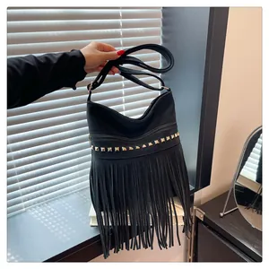 Détail macro d'un sac en cuir noir avec des rivets dorés et de longues franges de mode