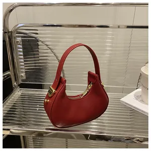 Detail of a red crescent hobo bag with smooth leather texture and golden zipper