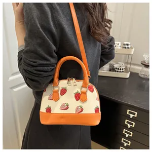 Detailed side view of the shell-shaped handbag with strawberry print on a female model