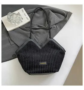 Detail of black corduroy tote bag with V-shaped opening and fashion leather label