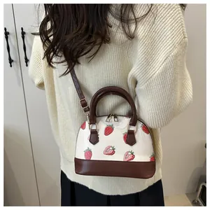 Detailed view of the strawberry print shell bag worn by model showing its compact size