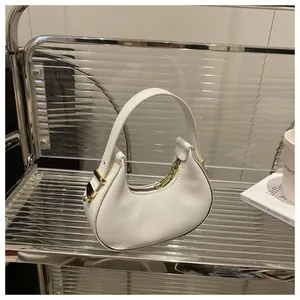Close-up of a white half-moon handbag with gold hardware on a stylish display