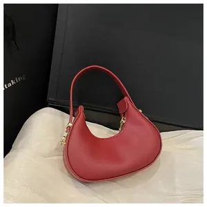 Close-up of a red crescent handbag with smooth faux leather texture and golden zipper