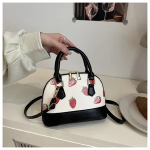Detail of shell handbag featuring strawberry print and black contrast stitching finish