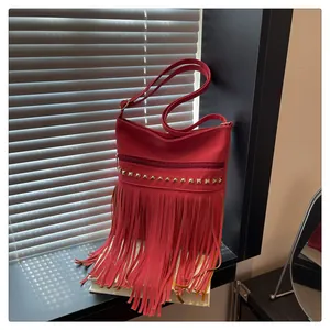 Détail du sac à bandoulière rouge avec franges, clous dorés et sangle réglable en PU