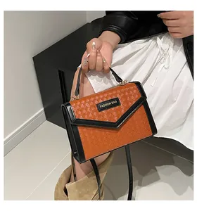 Detail of orange woven texture handbag with black contrast trim and Fashion Bag plaque