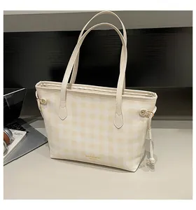 Detail of yellow and white checkered tote bag featuring a brand logo and tassel decoration
