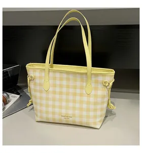 Detail of yellow and white checkered tote bag featuring a brand logo and side drawstring