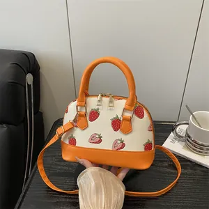 Textured strawberry print shell bag in orange and white with top handles and strap