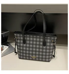 Close-up of black and grey checkered tote bag featuring gold buckle and leather handle