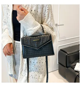 Detailed view of black woven texture leather handbag with gold 'FASHION BAG' metal plaque