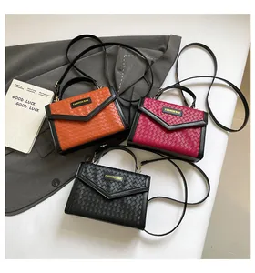 Close-up of woven texture handbags in orange, magenta, and black with V-shaped flaps