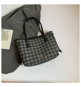 Detail of grey checkered tote bag with gold logo and black leather drawstring accents