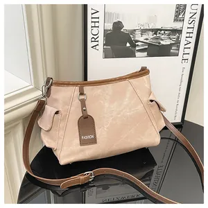 Detail van de contrastnaden en zijzakken van een beige en bruine bucket bag