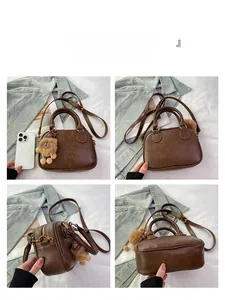 Macro detail of retro brown leather mini Boston bag with plush bear charm accessory