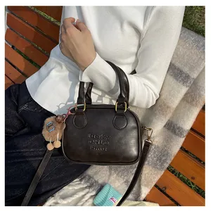 Detail of dark brown matte square bag with lucky engraving and plush bear charm