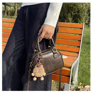 Detail of dark brown leather mini Boston bag with lucky brand embossing and bear charm