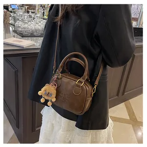 Brown leather crossbody bag detail featuring lucky CHILD Bear embossing and plush lion charm