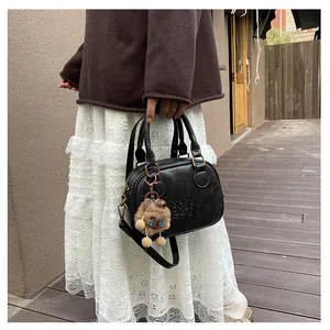 Detail of black semi-circular crossbody bag with LUCKY OHLO SMU embossing and bear charm