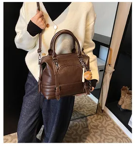 Bruine kunstleren Boston-tas met aardbei-bedeltje en schouderband gedragen door een model