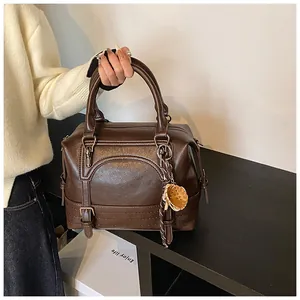 Detail van bruine Boston-tas van oliewasleer met dubbele handvatten en decoratieve hanger