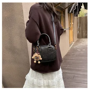 Chic black mini bag with round handles and teddy charm styled with a casual outfit