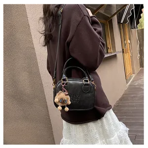 Detail of black faux leather square bag with dual handles and plush charm accessory