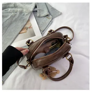 Detail view of compact dark brown crossbody bag interior showing phone and cosmetics