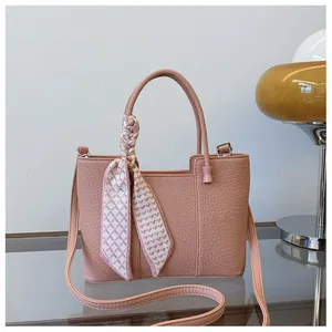Sac seau rose à texture litchi avec un foulard en soie géométrique sur la poignée
