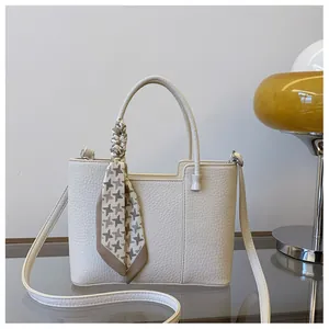Détail d'un sac à main en cuir beige avec foulard pied-de-poule et accessoires argentés