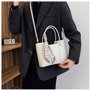 Détail du sac seau en cuir litchi blanc avec foulard en soie décoratif sur la poignée