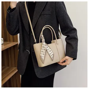 Détail du sac à main en cuir beige avec foulard pied-de-poule et bandoulière amovible