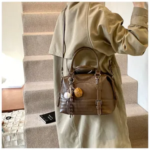 Detailopname van bruine vintage Boston tas met decoratieve bedeltjes op het model