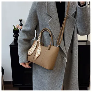 Sac seau en cuir marron avec détail de foulard en soie géométrique, porté avec un manteau gris