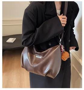 Détail du sac cabas en cuir marron foncé avec boucle métallique et breloque ours en peluche