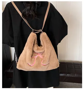Dettaglio della borsa tote in peluche marrone con ricamo a fiocco rosa e tracolla in pelle