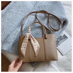 Détail du sac seau marron texturé avec foulard pied-de-poule et doubles poignées