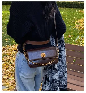 Close-up of a vintage dark brown shoulder bag with a gold chain and metal clasp