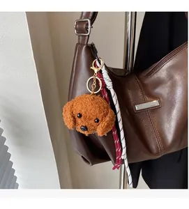 Détail d'un charm chien en peluche marron avec fermoir doré sur un sac en cuir