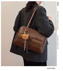 Side view of deep brown vintage tote bag with twin front pockets and bear charm detail