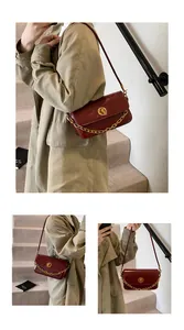 Detail of burgundy glossy leather shoulder bag with gold chain and metal twist lock