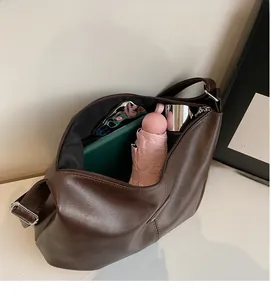 Vue de dessus du grand sac cabas marron contenant un parapluie et un carnet