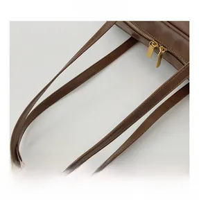 Close-up of vintage brown leather bag featuring dual gold zippers and slim shoulder straps