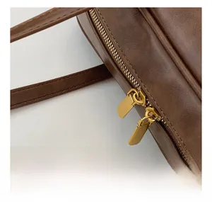 Detailed close-up showing the smooth golden dual zippers on a dark brown vintage bag